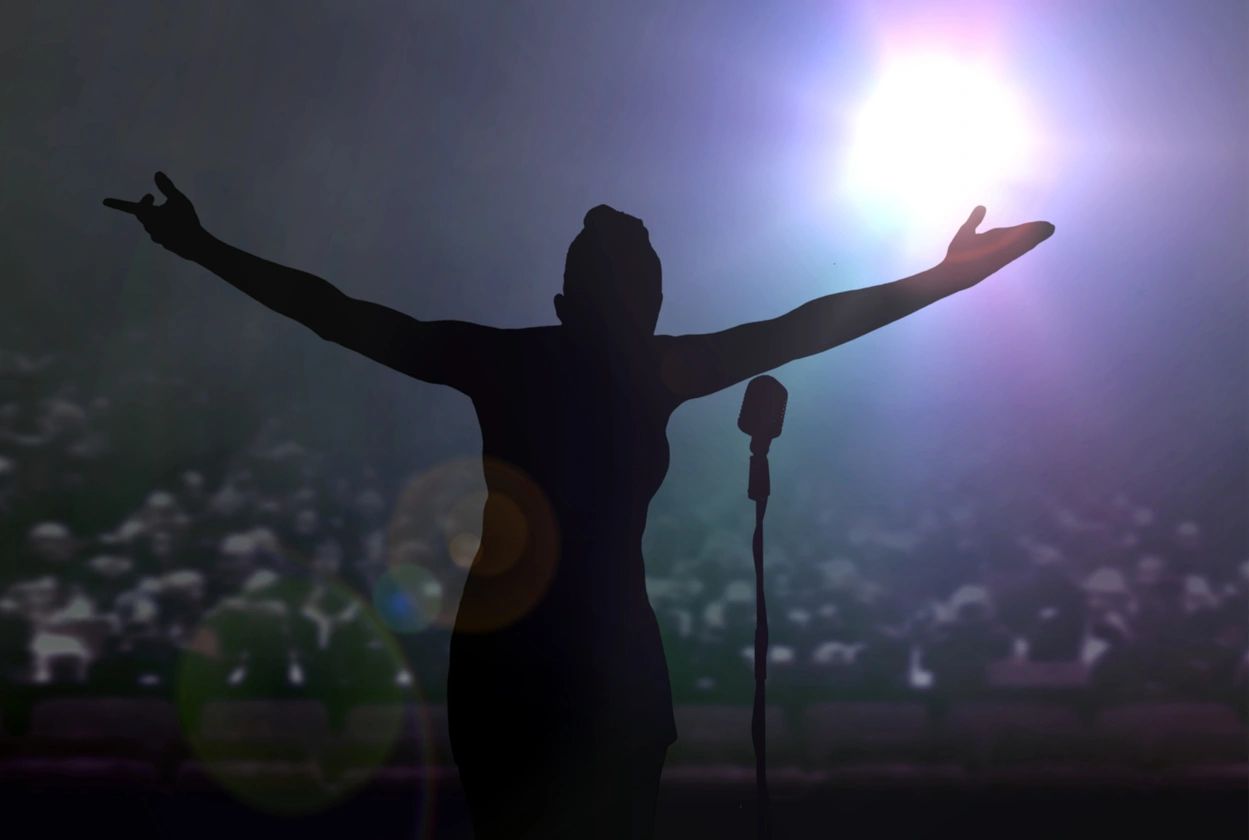 A person standing on stage with their arms outstretched.