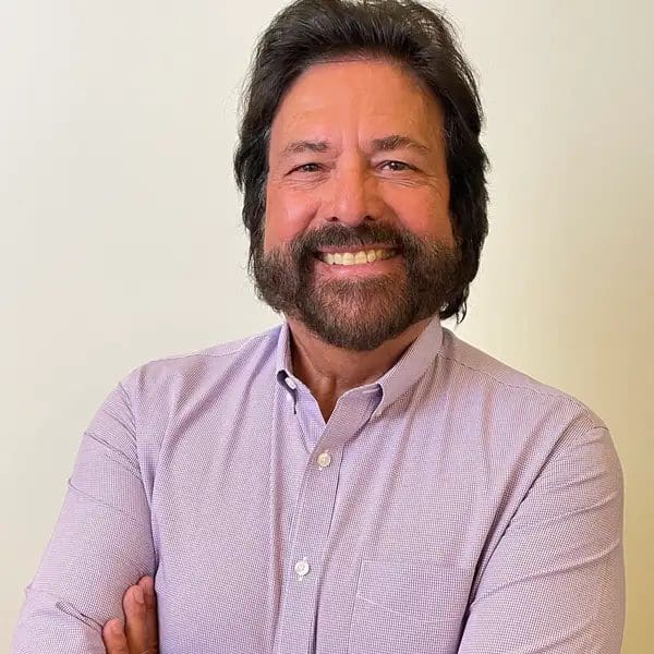 A man with long hair and beard smiling for the camera.